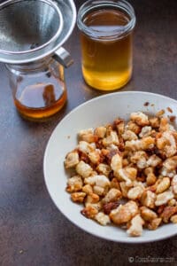 Los chicharrones en un plato delante de 2 tarros de a¡manteca de cerdo