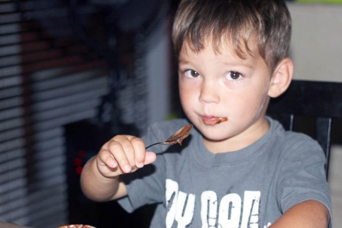 un niño pequeño comiendo mousse de chocolate