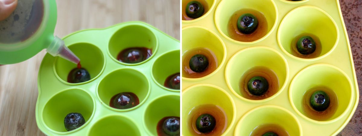 Añadiendo gelatina roja alrededor de los arándanos en moldes verdes de silicona con forma de semiesferas para formar las pupilas y los iris de los ojos de gelatina.