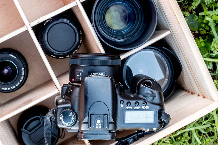 Una cámara encima de una caja de madera llena de diferentes objetivos