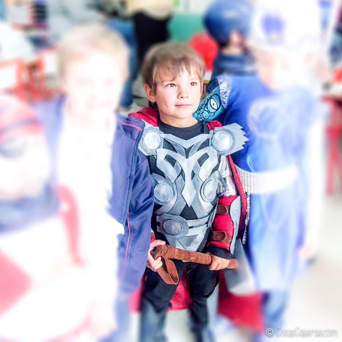 Un niño vestido con un disfraz de Thor que sostiene un martillo.