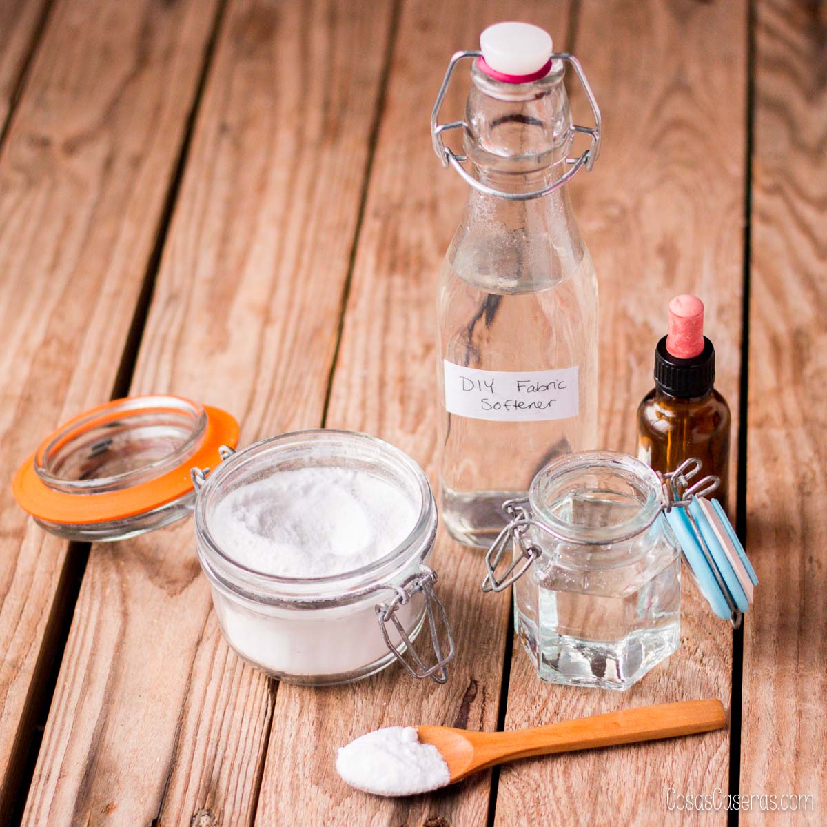 Ingredientes para suavizante natural de ropa: vinagre, bicarbonato, glicerina y aceite esencial sobre mesa de madera