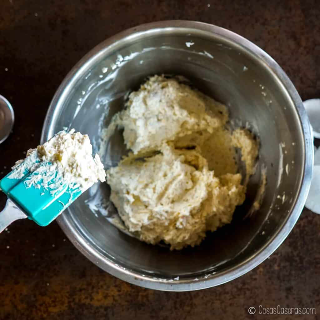 Usando una espátula para dividir la mezcla de queso crema en 2 partes desiguales