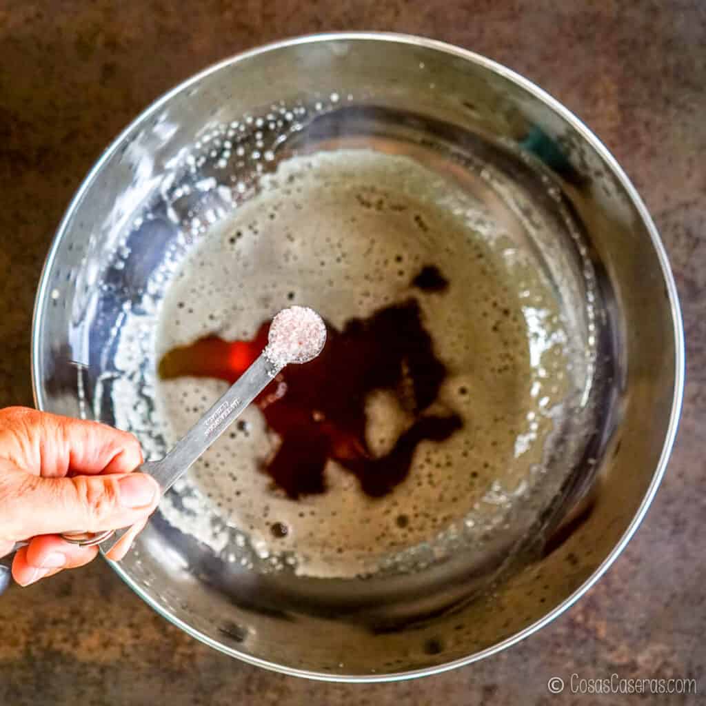 Vista aérea de sal en una cuchara medidora, sobre una mezcla de miel en un bol.