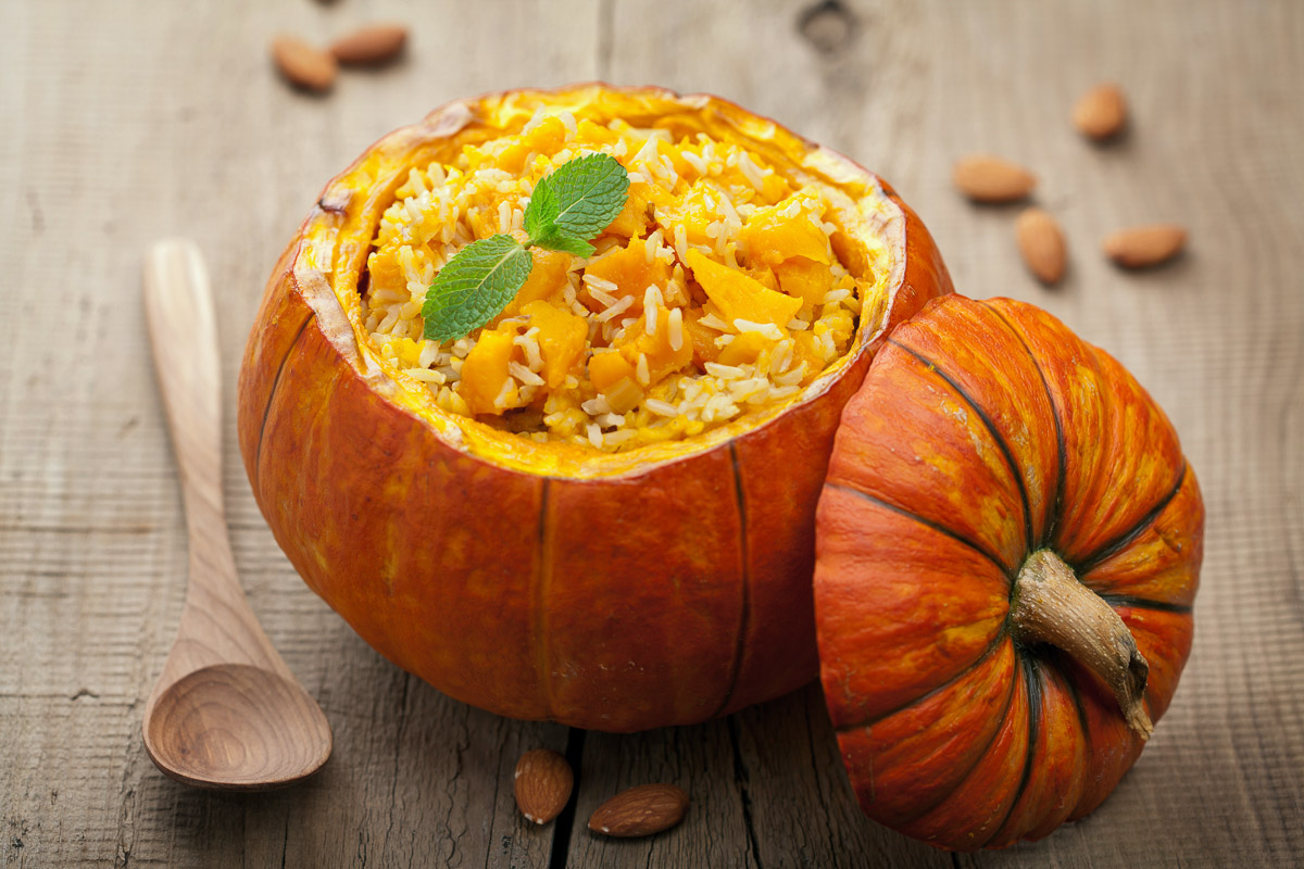 Calabaza pequeña vaciada y utilizada como cuenco para servir un plato de arroz con verduras en Halloween.