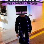 Niño con un disfraz casero de Enderman de Minecraft, con cabeza cuadrada negra, ojos morados pixelados y luces LED violetas. Texto: «Disfraz de Minecraft Enderman – Fácil, cómodo, sin coser».