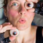 Una persona que sogominolas con forma de ojo delante de la cara.